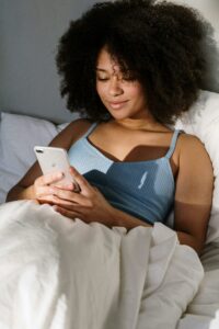 Lady using an iPhone in bed